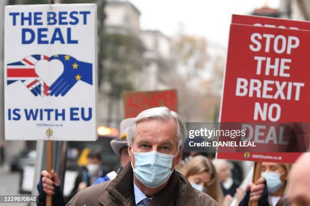 An Anti-Brexit demonstrator hold placards as EU chief negotiator Michel Barnier , wearing a protective face covering to combat the spread of the...