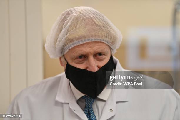 Prime Minister Boris Johnson, wearing a hair net and face covering reacts as he views the last minute quality testing of the 'fill and finish' stage...