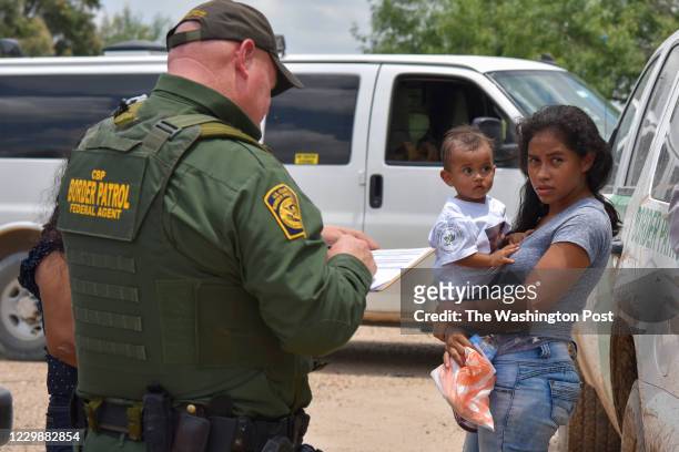 Young mother from Honduras and her 1-year-old child are detained by United States Border Patrol after rafting across the Rio Grande on the...