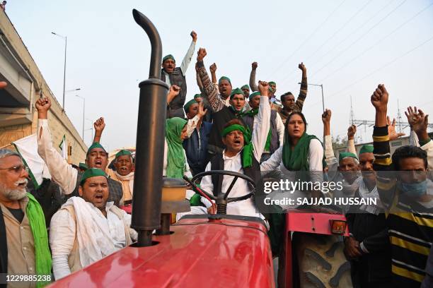 Farmers on a tractor trolley shout slogans near a police road block stopping them from marching to New Delhi to protest against the central...