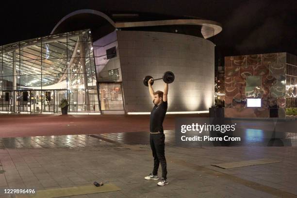 Man lifts weights outside of the van Gogh Museum on December 1, 2020 in Amsterdam, Netherlands. As of December 1st, face masks become compulsory in...