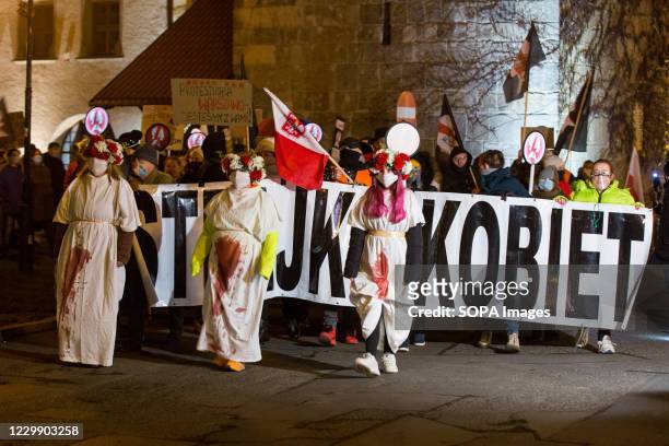 Women in bloodstained white robes with wreaths on their heads take part during the Women's Strike. 'You will never walk alone', under this slogan,...