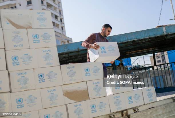 Man carrying a box of relief supplies during the food distribution. Palestinians receive food aid from a distribution center affiliated with the...
