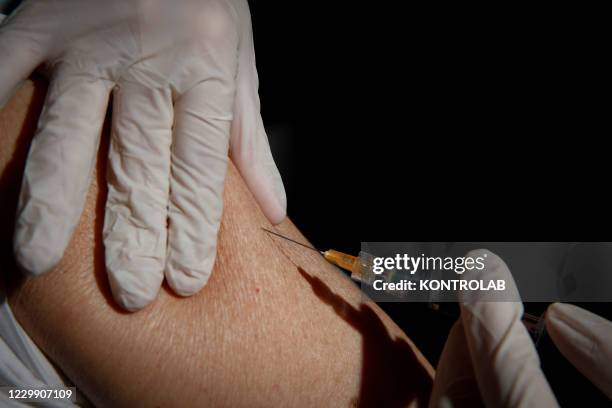 Seasonal influenza vaccine, is administered with a syringe at a doctor's surgery in Naples city. The influenza viruses that infect people change...