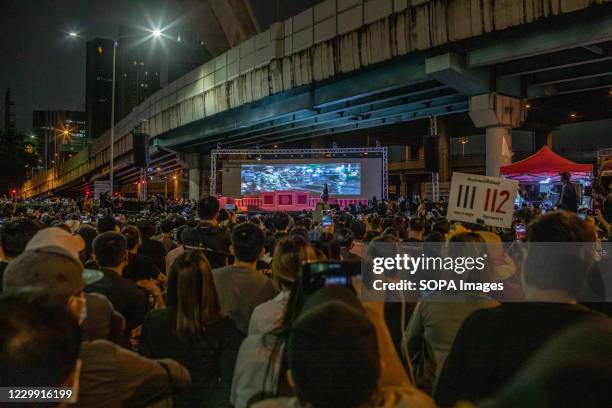 Pro-democracy protesters listen to activist Panusaya 'Rung' Sithijirawattanakul while watching a movie on the conflict between The Thai army and the...