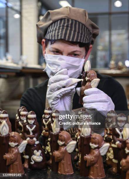 December 2020, Brandenburg, Hornow: Anne Walter, chocolatier from the Confiserie Felicitas, decorates small Christmas figures with a mouth and nose...