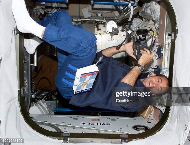 Space shuttle Endeavour French Mission Specialist Philippe Perrin 12 June 2002 holds a camera while floating in the hatch between the Unity node and...