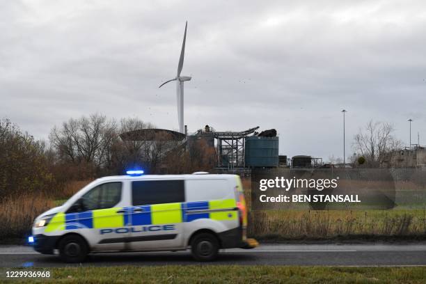 Police van drives by with at a waste water treatment plant in the background showing a damaged silo in Avonmouth, near Bristol in southwest England...