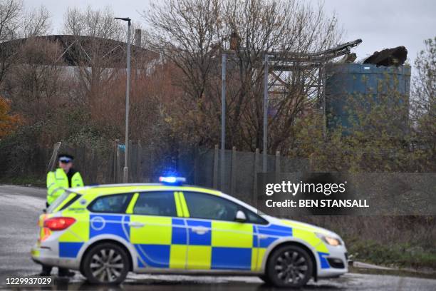 Police officer staffs a cordon with a damaged silo seen in the background at a waste water treatment plant in Avonmouth, near Bristol in southwest...