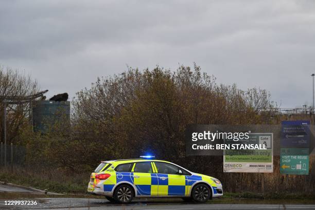 Police officer staffs a cordon with a damaged silo seen in the background at a waste water treatment plant in Avonmouth, near Bristol in southwest...
