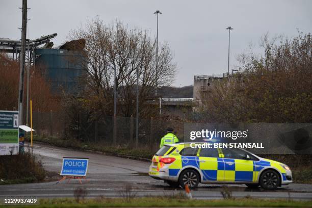 Police officer staffs a cordon with a damaged silo seen in the background at a waste water treatment plant in Avonmouth, near Bristol in southwest...
