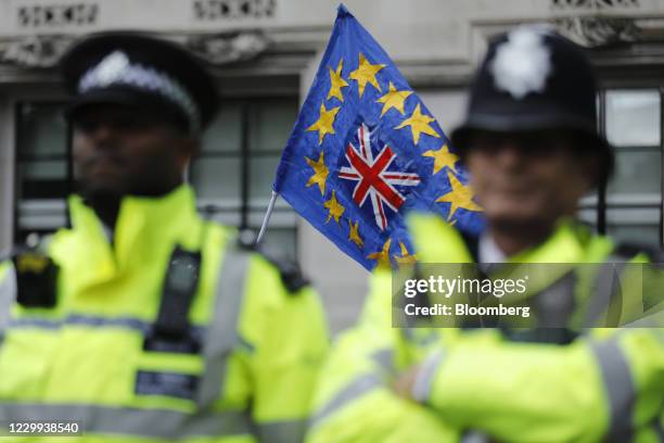 European Union and Union Jack flag design flies behind police officers during a People's Vote march in London, U.K., on Saturday, Oct. 19, 2019....