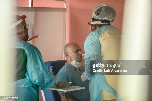 Health worker from the Alberto Torres hospital wearing PPE performs a COVID-19 testing to a patient on December 4, 2020 in Sao Goncalo, Brazil. The...
