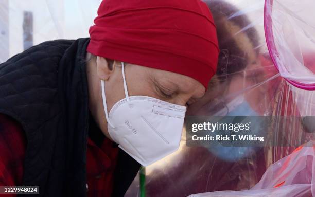 Mary Zoller hugs her 93 year old father, George Dvirak, through the wall of a plastic "hug tent" outside the Accel at Longmont skilled nursing...