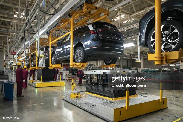 Employees install batteries onto an electric sport utility vehicle during a media tour of the Nio Inc. Production facility in Hefei, Anhui province,...