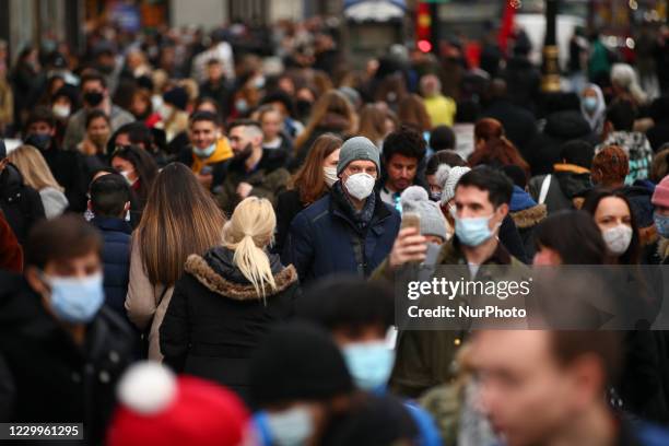 Shoppers, some wearing face masks, walk along a busy Oxford Street in London, England, on December 5, 2020. London has returned to so-called Tier 2...