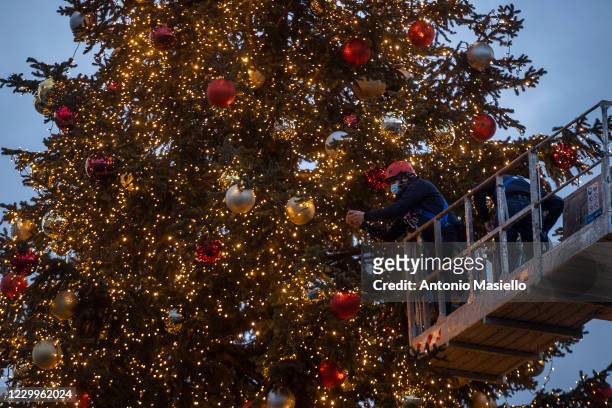 Municipal workers put up decoration on the big and official Christmas tree so called "Spelacchio" at Piazza Venezia during the restrictions to...