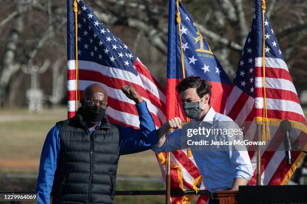 Democratic U.S. Senate candidates Raphael Warnock and Jon Ossoff bump elbows during an outdoor drive-in rally on December 5, 2020 in Conyers,...