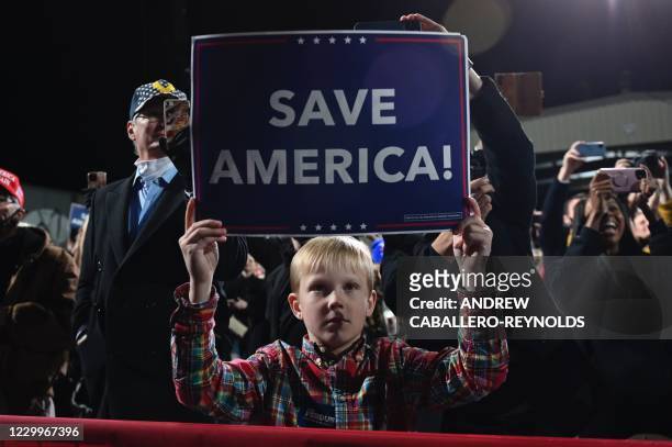 Boy holds a "Save America" sign as US president Donald Trump speaks at a rally to support Republican Senate candidates at Valdosta Regional Airport...