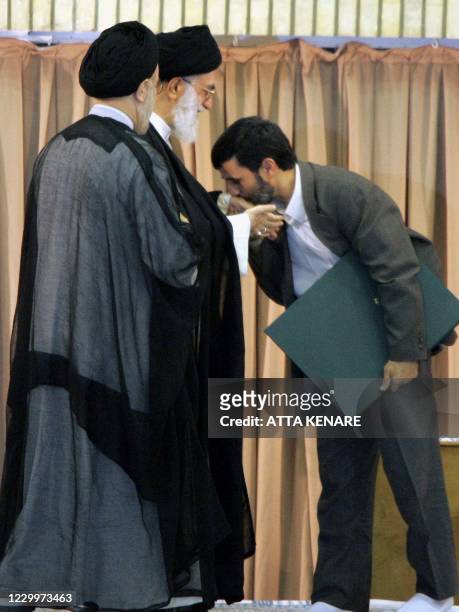 Iran's new President Mahmood Ahmadinejad kisses the hand of Iranian Supreme Leader Ayatollah Ali Khamenei during a ceremony to formally install the...