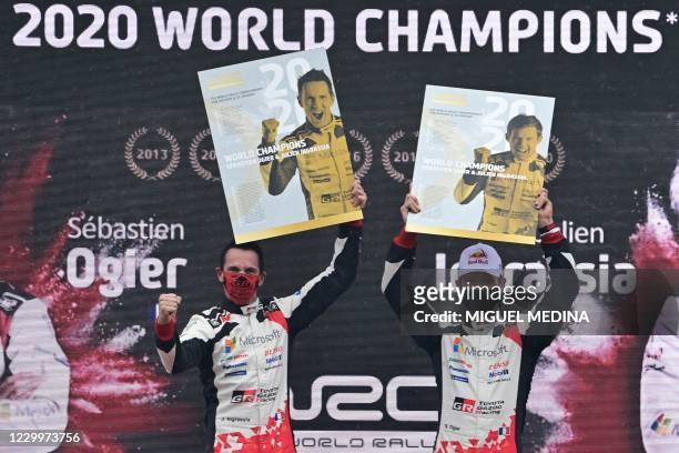 Winners French driver Sebastien Ogier and his co-driver Julien Ingrassia hold placards on the podium after winning the FIA World Rally Championship...