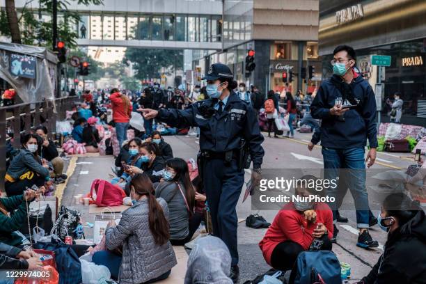 Police officer is seen reminding migrant workers who are sitting on the road to maintain social distance and not to violate the 2 people gathering...