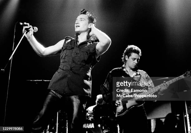 Bono, Irish musician and philanthropist performing on stage alongside U2 bass guitarist Adam Clayton on November 16, 1984.