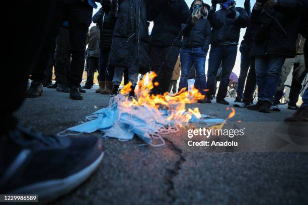 Anti-lockdown demonstrators burn face masks as they are gathered at the Grand Army Plaza to protest coronavirus restrictions in Brooklyn, New York,...