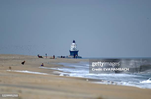 People enjoy the beach on the Atlantic Ocean at Cape Henlopen State Park, in Lewes, Delaware, November 25, 2020. - The new Harbor of Refuge light,...