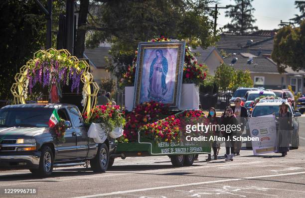 Wearing masks, participants normally walking, drive decorated vehicles in the annual Procession and Mass in honor of Our Lady of Guadalupe tp the...