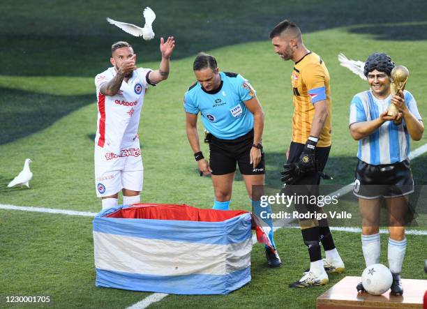 Referee Patricio Loustau and team captains Miguel Torren of Argentinos and Mariano Andujar of Estudiantes free white pidgeos paying tribute to the...