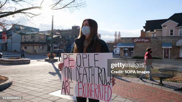 Woman wearing a face mask holds a placard in Peoples Park to protest against the death penalty, and a wave of executions at the Terre Haute federal...