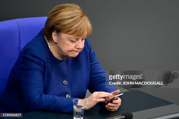 German Chancellor Angela Merkel checks her mobile phone as she attends a debate at the Bundestag in Berlin on December 8, 2020.