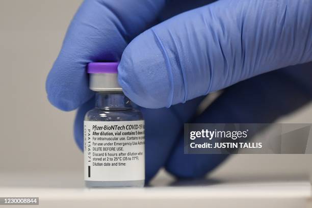 Member of staff poses with a phial of Pfizer-BioNTech Covid-19 vaccine at a vaccination health centre in Cardiff, South Wales' on December 8, 2020. -...