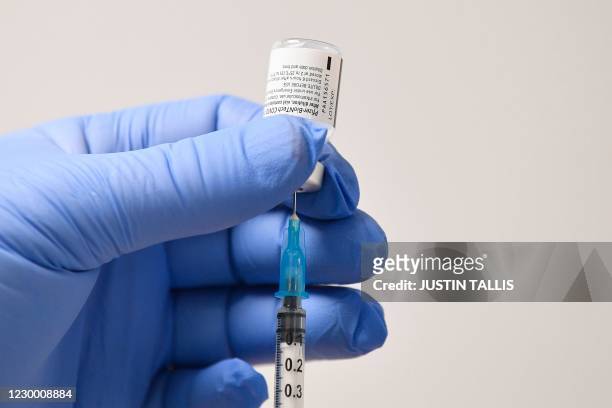 Member of staff uses a needle and a phial of Pfizer-BioNTech Covid-19 vaccine to prepare a dose at a vaccination health centre in Cardiff, South...