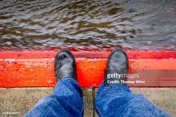person looking down at red curb and rain water - wet jeans stock-fotos und bilder