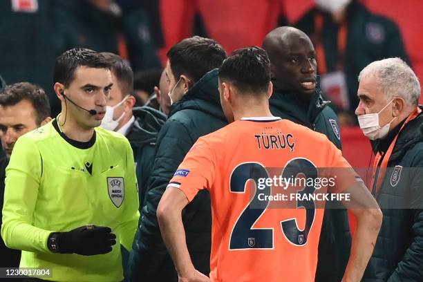 Romanian referee Ovidiu Hategan talks to Istanbul Basaksehir FK staff members past Istanbul Basaksehir's French forward Demba Ba during the UEFA...