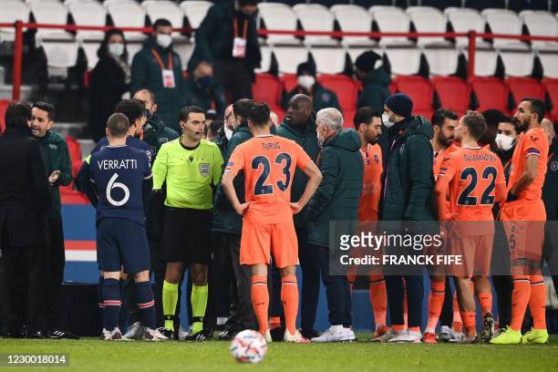 Romanian referee Ovidiu Hategan talks to Istanbul Basaksehir's staff members past Istanbul Basaksehir's French forward Demba Ba during the UEFA...