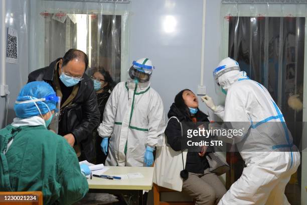 This photo taken on December 8, 2020 shows a health worker conducting a nucleic acid test on a resident in Chengdu, in western China's Sichuan...