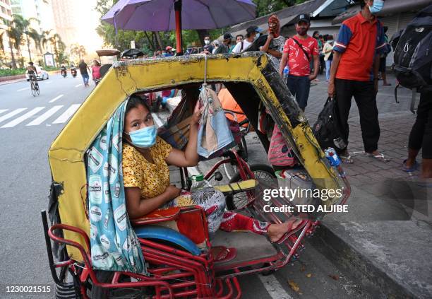 In this photo taken on November 24 a woman attends to her child inside their tricycle, serving as their home, while her husband queues for free...