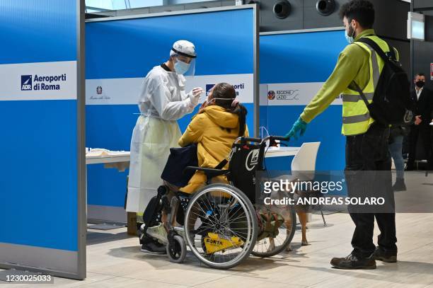 Disabled passenger who just landed from New York on an Alitalia flight undergoes a rapid antigen swab test for COVID-19 on December 9, 2020 at a...