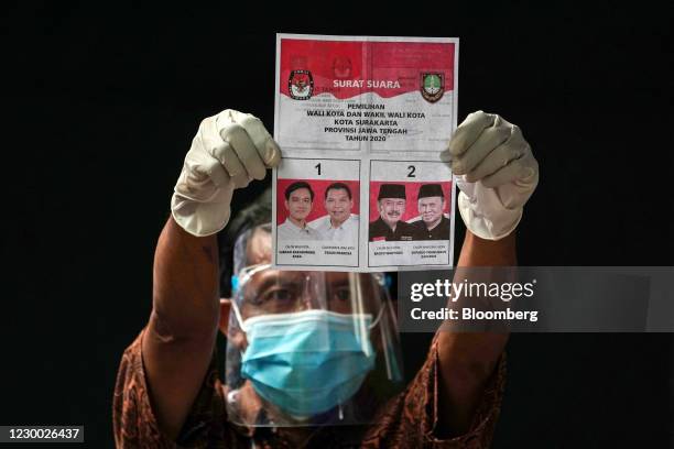 An election official holds a ballot paper at a polling station in Solo, Central Java, Indonesia, on Wednesday, Dec. 9, 2020. The president's eldest...