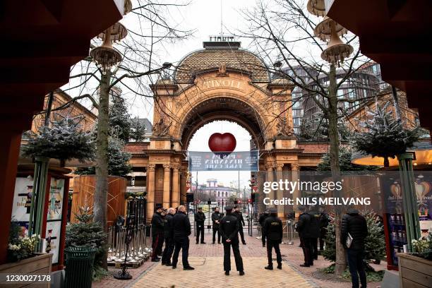 Employees of the Tivoli Gardens stand at the closed entrance to the amusement park in Copenhagen on December 9 as the park closes for Christmas and...