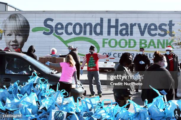 Volunteers load boxes of food assistance into cars at the Share Your Christmas food distribution event sponsored by the Second Harvest Food Bank of...