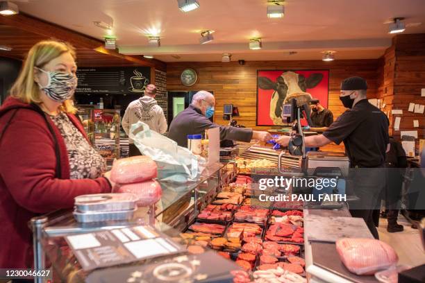 Customers wait to buy meats including sausages and burgers at the counter of McAtamney's butcher's shop in Ballymena, Northern Ireland, on December...