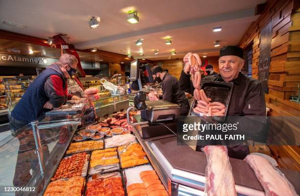 Butcher Kieran McAtamney poses for a photograph holding pork sausages at his butcher's shop in Ballymena, Northern Ireland, on December 10, 2020. The...