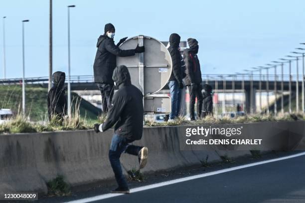 Migrants run across the A 16 motorway in an attempt to climb into the back of lorries bound for Britain while traffic is stopped upon waiting to...