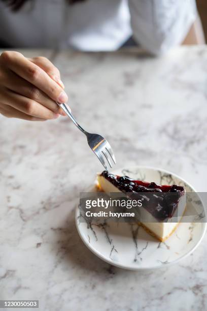 young woman eating blueberry cheesecake with a fork - cheesecake stock pictures, royalty-free photos & images