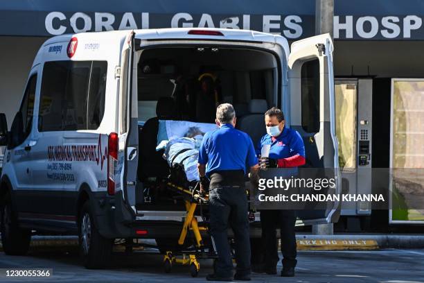 Medics transfer a patient on a stretcher from an ambulance outside of Emergency at Coral Gables Hospital where Coronavirus patients are treated in...