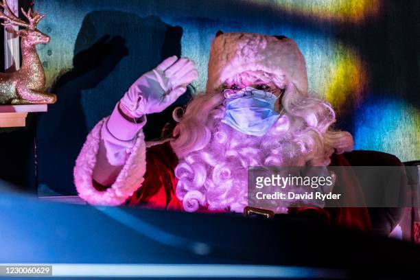 Person dressed as Santa waves to passing cars at Starlight Lane, a drive-through Christmas event, at the Lumen Field Event Center Parking Garage on...